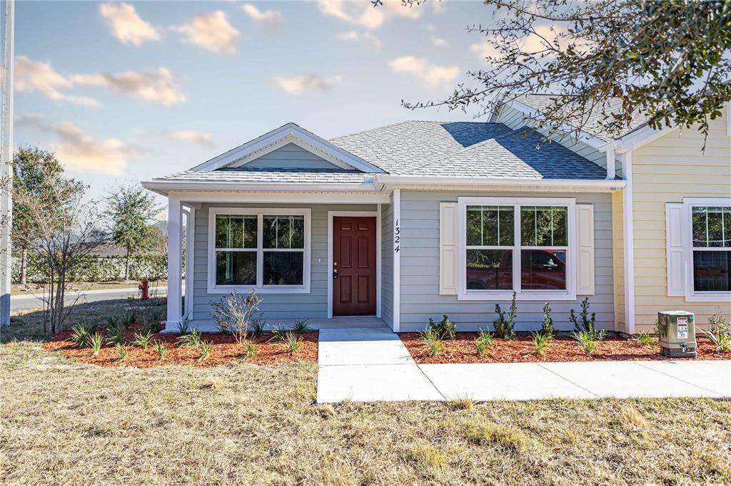 A single-story house with light blue siding, a red front door, and a concrete walkway — 1342 COTTAGE CIRCLE, TAVARES, FL