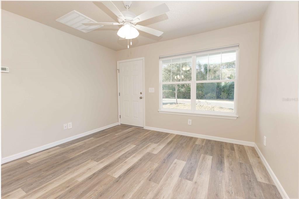 An empty room with light-colored walls, wood-look flooring, a ceiling fan, and a window — 1342 COTTAGE CIRCLE, TAVARES, FL