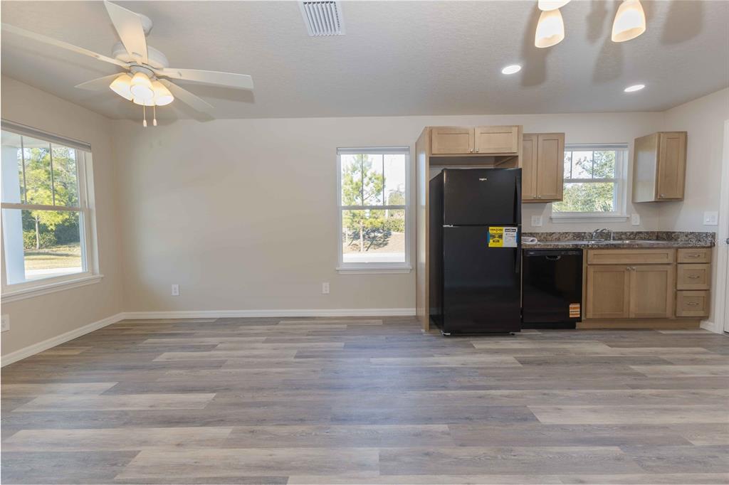 A kitchen and dining area with light wood cabinets, black appliances, and wood-look flooring — 1342 COTTAGE CIRCLE, TAVARES, FL