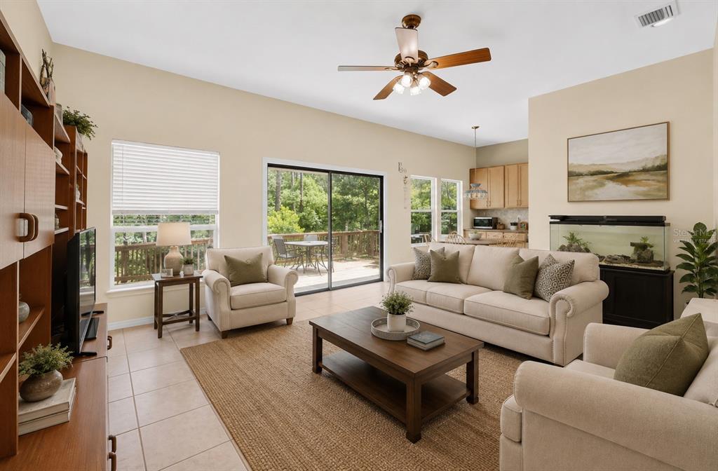 A living room with beige walls, tile floors, a ceiling fan, and a sliding glass door — 325 NW 80TH BOULEVARD, GAINESVILLE, FL