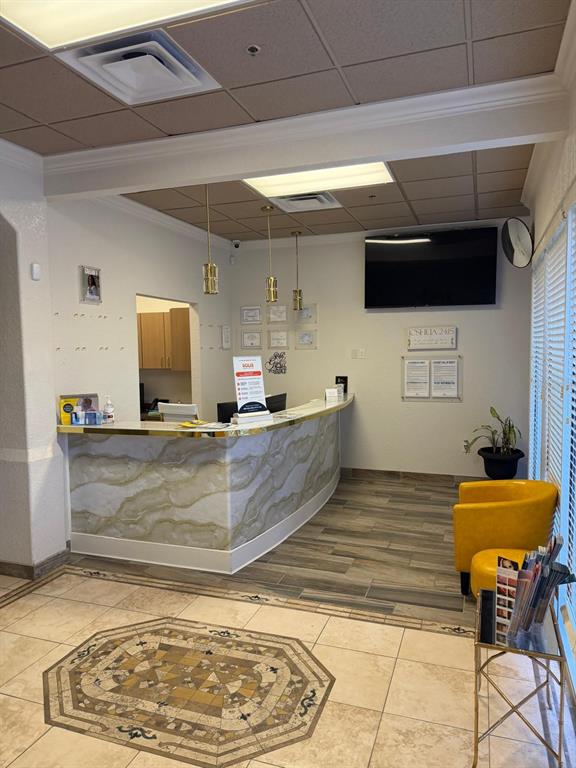 A reception area features a curved marble-patterned desk, yellow chairs, and a tiled floor — 8010 SUNPORT DRIVE UNIT 116, ORLANDO, FL