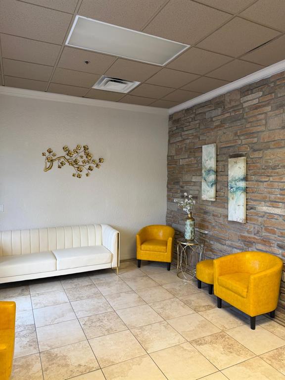 A waiting area features a white sofa, two yellow armchairs, and a stone accent wall — 8010 SUNPORT DRIVE UNIT 116, ORLANDO, FL