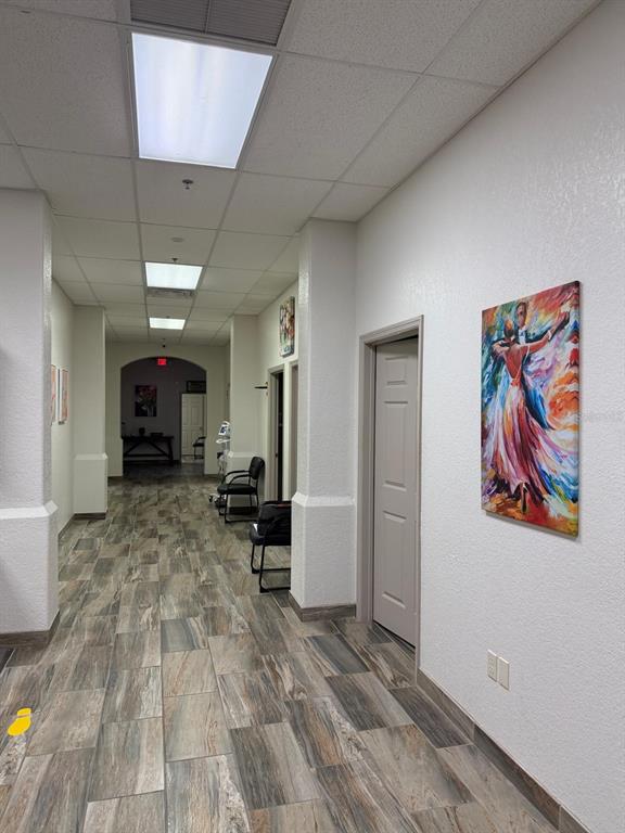 A hallway with wood-look tile flooring, white walls, recessed lighting, and framed artwork — 8010 SUNPORT DRIVE UNIT 116, ORLANDO, FL