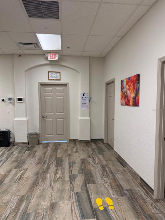 A waiting room features wood-look tile flooring, two doors, an eye chart, and wall art — 8010 SUNPORT DRIVE UNIT 116, ORLANDO, FL