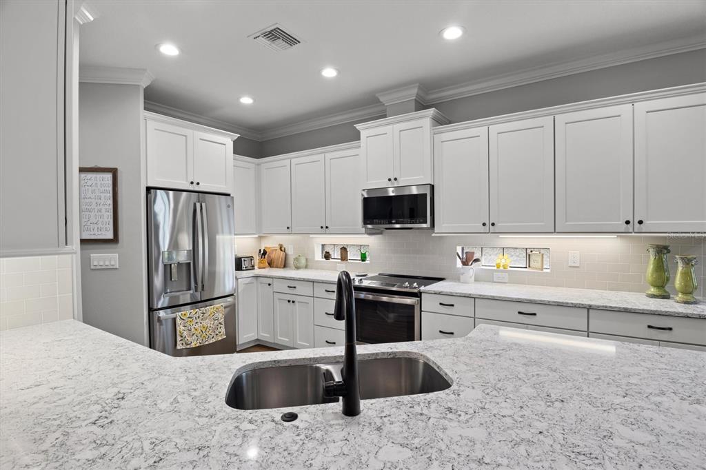 A kitchen features white cabinets, granite countertops, stainless steel appliances, and a central island sink — 7953 LAKE JAMES BOULEVARD, LAKELAND, FL