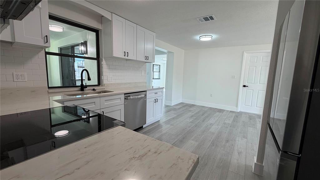 A kitchen with dark cabinets and stainless steel appliances is viewed through an arched doorway — 177 TRINITY RIDGE CIRCLE, DAVENPORT, FL