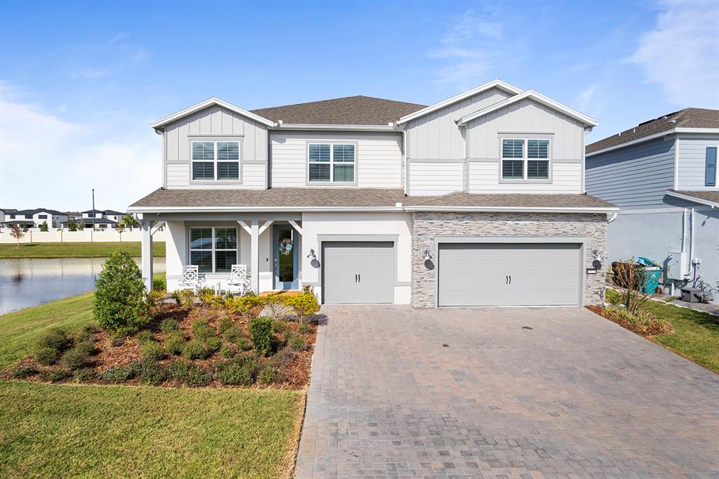 A two-story suburban house features a stone-accented facade, a three-car garage, and a paved driveway — 13726 TYBEE BEACH LANE, ORLANDO, FL