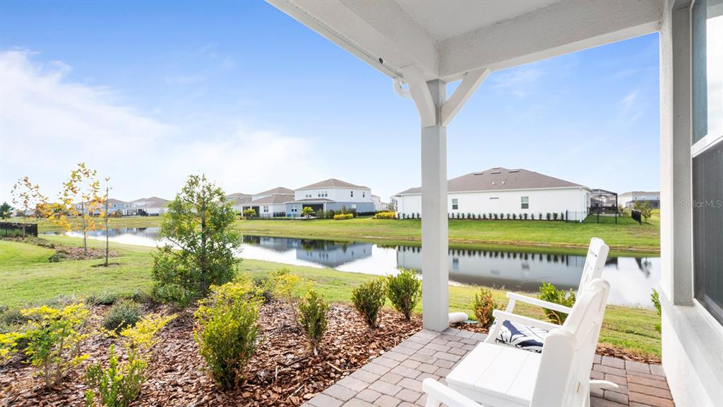 A covered patio overlooks a pond with houses in the background — 13726 TYBEE BEACH LANE, ORLANDO, FL