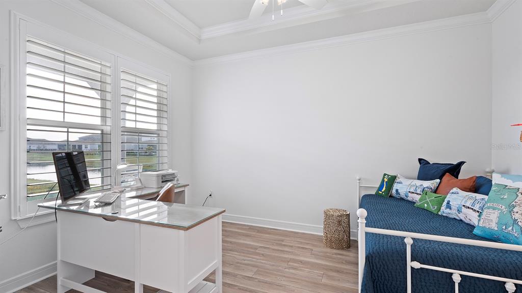 A bedroom with a desk, a daybed, white walls, and wood-look flooring — 13726 TYBEE BEACH LANE, ORLANDO, FL