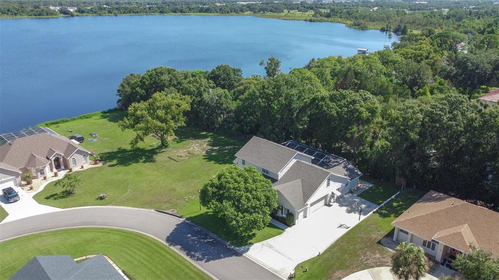 An aerial view shows a suburban house with a pool cage near a large lake — 1016 S LAKE MARIAM DRIVE, WINTER HAVEN, FL
