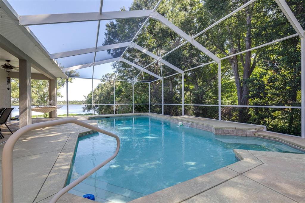 A screened-in swimming pool patio overlooks a lake surrounded by trees — 1016 S LAKE MARIAM DRIVE, WINTER HAVEN, FL