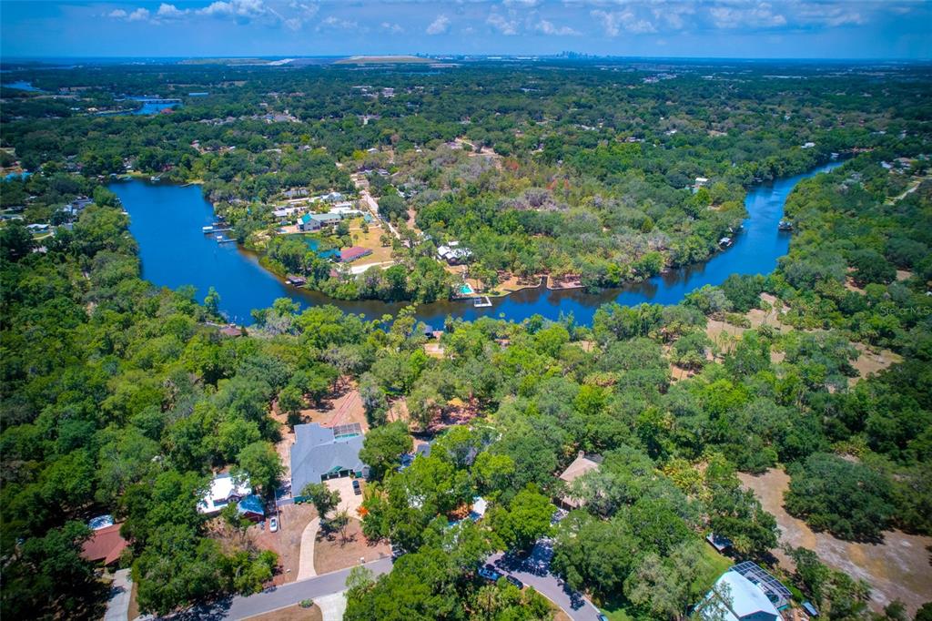 An aerial view shows a winding river flowing through a dense, tree-covered residential landscape — 11526 RIVER COUNTRY DRIVE, RIVERVIEW, FL