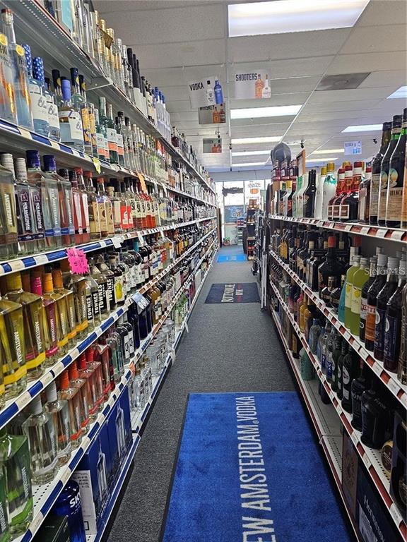 A liquor store aisle features shelves stocked with various bottles of spirits and blue floor mats — # CONFIDENTIAL, OVIEDO, FL