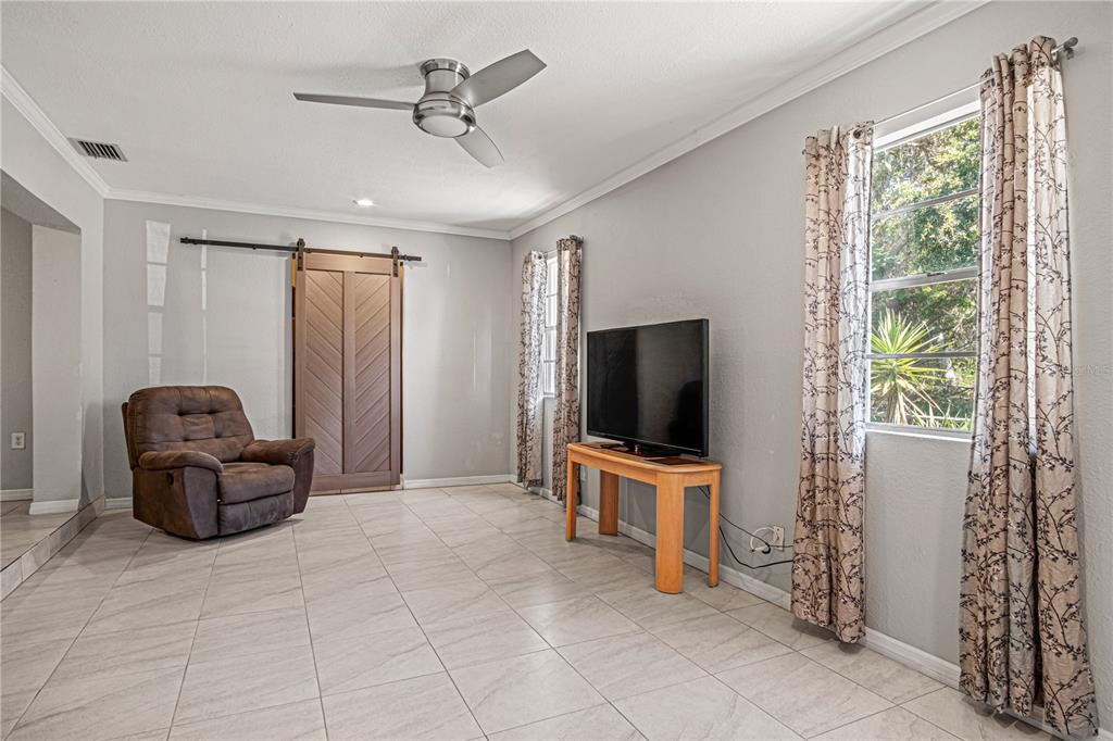 A living room features light tile flooring, a brown recliner, a television, and a barn door — 4588 PARKER AVENUE, ROCKLEDGE, FL