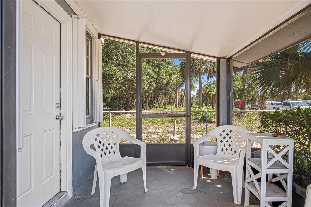 A screened-in porch features two white plastic chairs, a small side table, and a door — 4588 PARKER AVENUE, ROCKLEDGE, FL