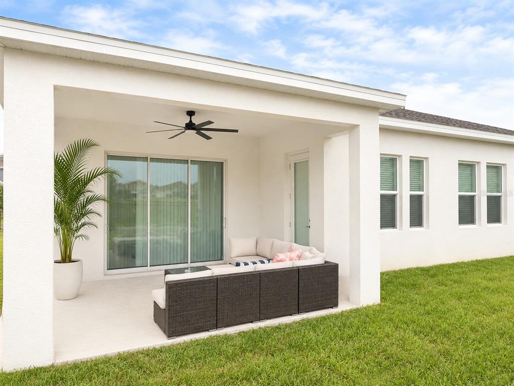 A covered patio features a dark wicker sectional sofa, a potted plant, and a ceiling fan — 4514 HILLINGDAM ROAD, DAVENPORT, FL