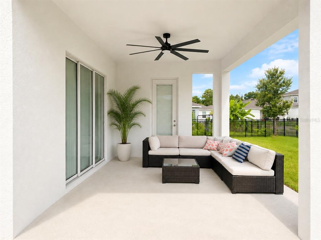 A covered patio features a sectional sofa, a coffee table, a ceiling fan, and a plant — 4514 HILLINGDAM ROAD, DAVENPORT, FL