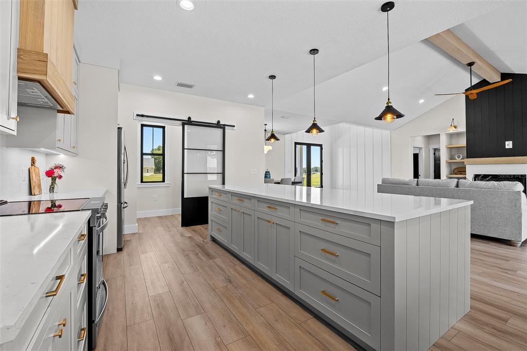 A modern kitchen features a large gray island, white countertops, and a black barn door — 845 NW COUNTRY LAKE DRIVE, LAKE CITY, FL