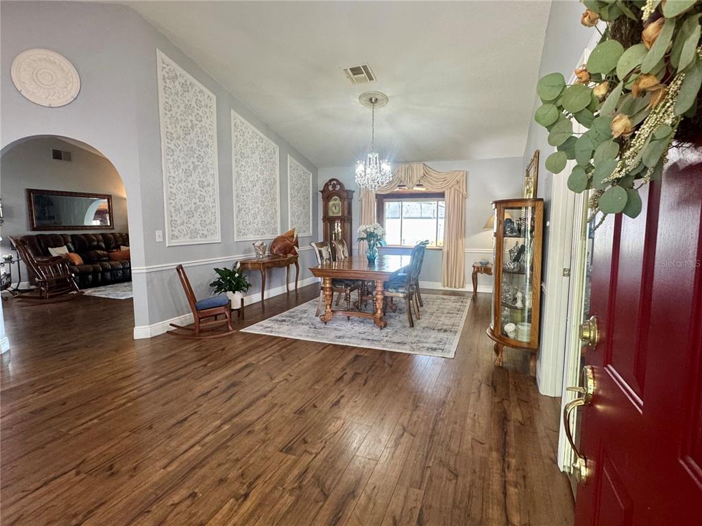 A dining room with wood floors, a chandelier, and a grandfather clock near an entryway — 9237 SABAL PALM CIRCLE, WINDERMERE, FL