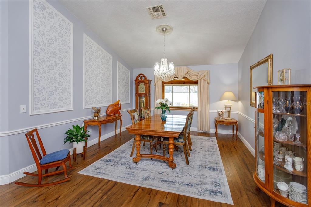 A formal dining room features a wooden table, a grandfather clock, and a crystal chandelier — 9237 SABAL PALM CIRCLE, WINDERMERE, FL