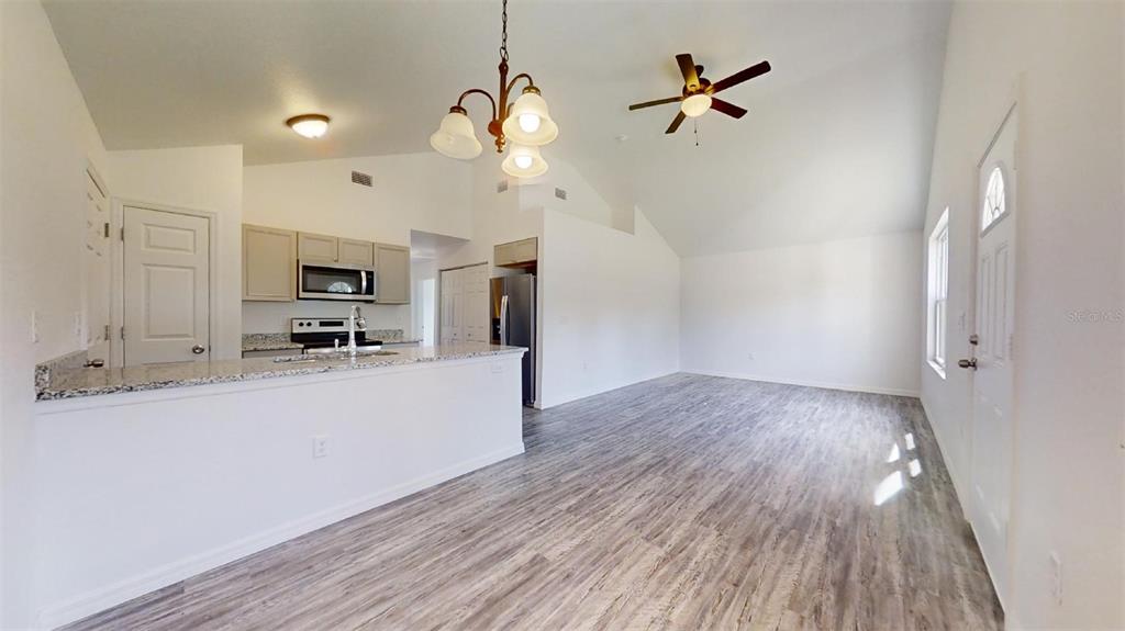 An open-concept kitchen and living area features light wood-look flooring and vaulted ceilings — 13752 SW 111TH STREET, DUNNELLON, FL