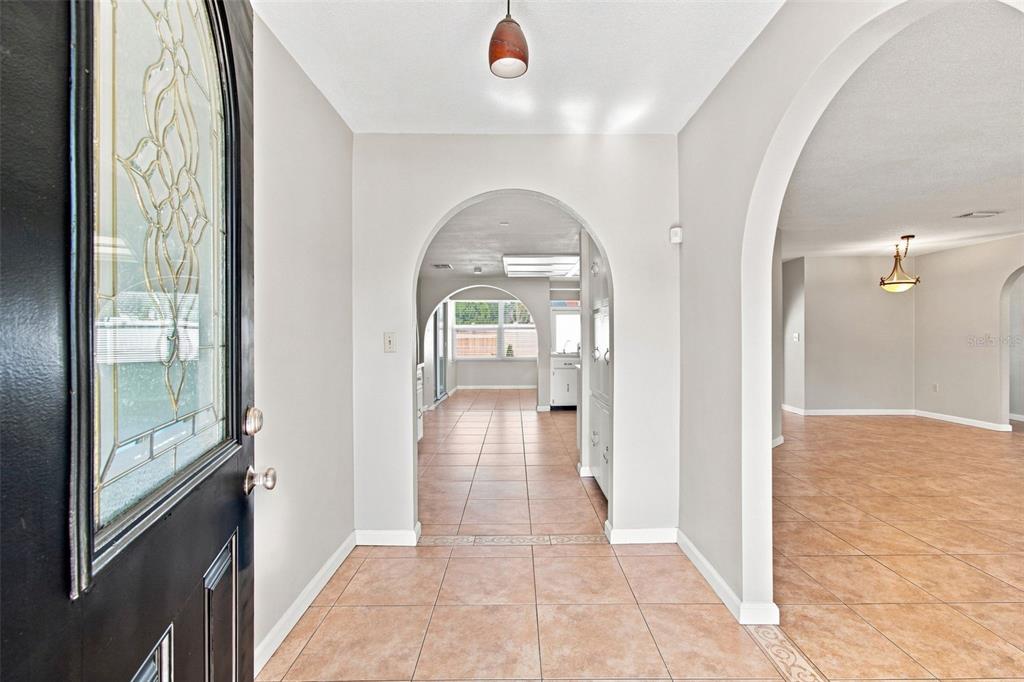 An entryway with tiled floors leads through an arched doorway into a kitchen and living area — 527 WAYFARER DRIVE, TARPON SPRINGS, FL