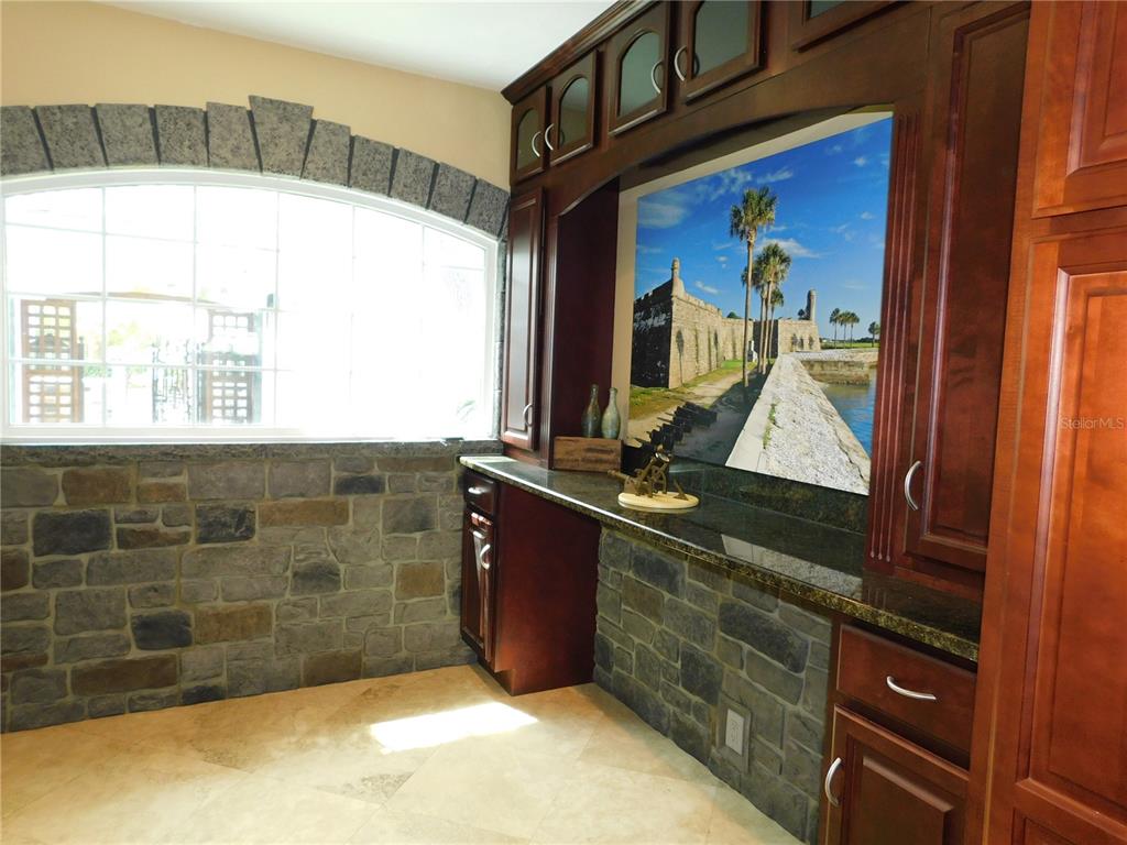 A room with stone walls, a large arched window, and dark wood cabinetry — 155 MARSHALL STREET, SAFETY HARBOR, FL