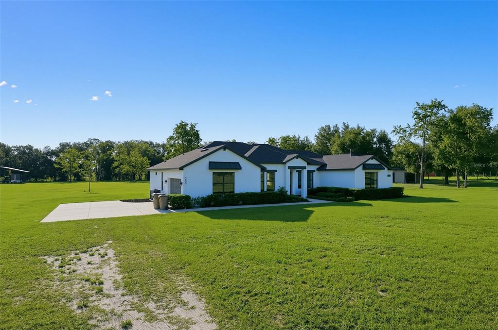 A white single-story house with a dark roof sits on a large, grassy lot — 4650 LAKE PICKETT DRIVE, GROVELAND, FL