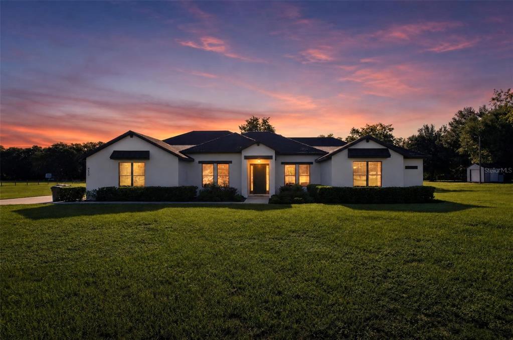 A single-story house with a white exterior and dark roof sits on a grassy lawn — 4650 LAKE PICKETT DRIVE, GROVELAND, FL