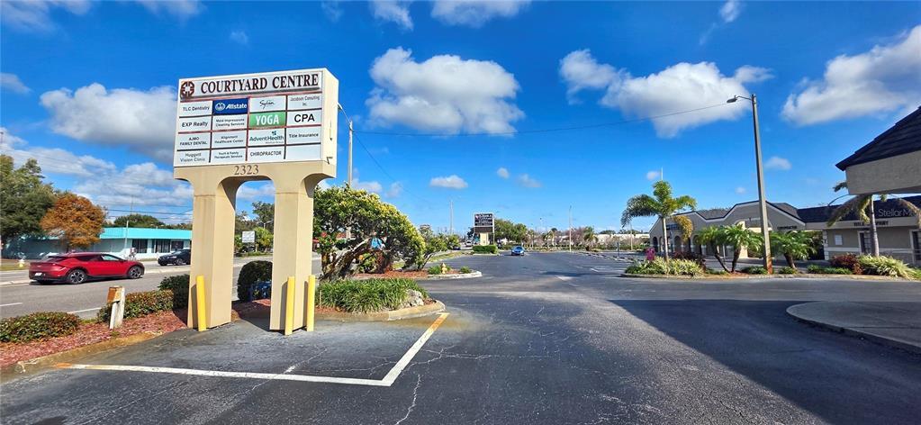 A sign for the Courtyard Centre stands in front of a parking lot and buildings — 2323 CURLEW ROAD UNIT 7B, DUNEDIN, FL