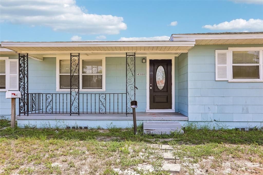 A light blue house features a front porch with decorative iron railings and a dark door — 4500 3RD AVENUE S, ST PETERSBURG, FL