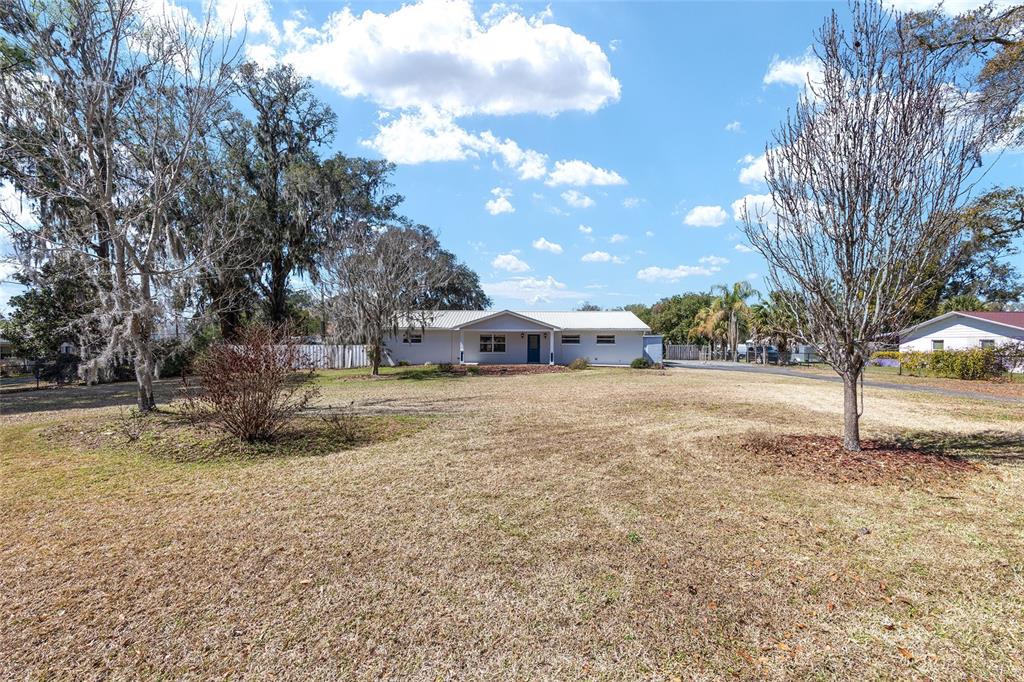 A single-story white house with a metal roof sits on a large, grassy lot — 10350 SE 43RD COURT, BELLEVIEW, FL