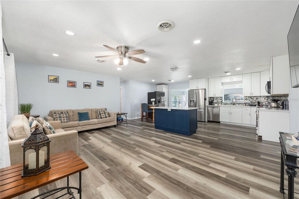 An open-concept living room and kitchen featuring wood-look flooring and a blue center island — 10350 SE 43RD COURT, BELLEVIEW, FL