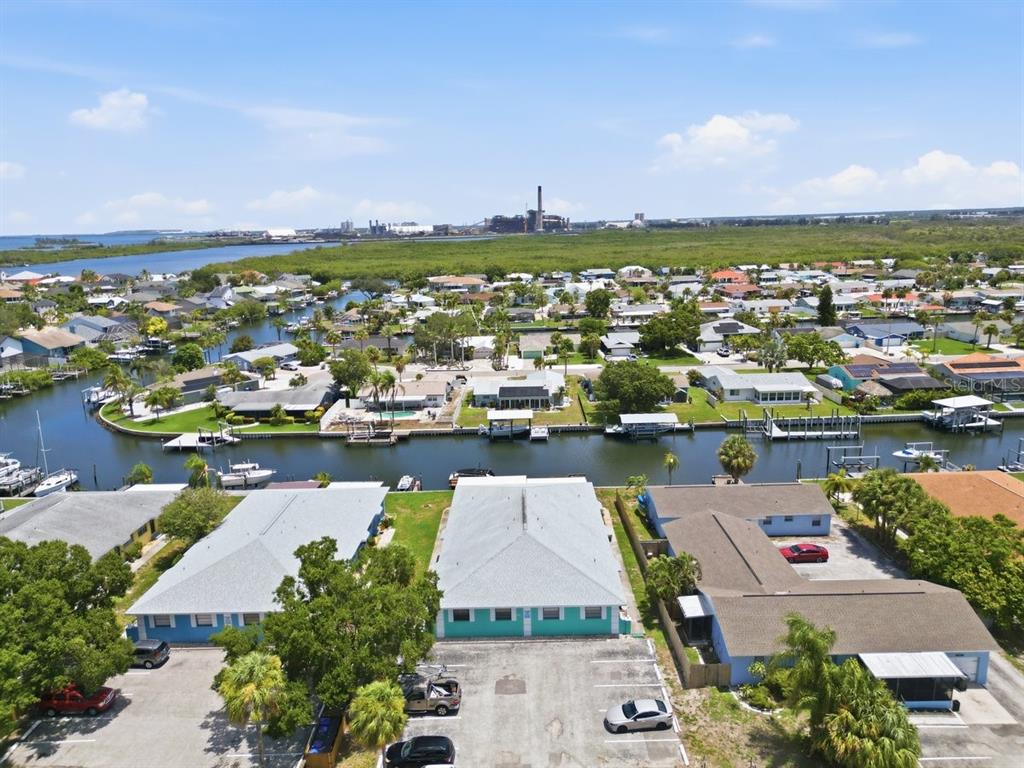 A canal view featuring wooden docks, a boat lift, and several boats under a blue sky — 1041 APOLLO BEACH BOULEVARD UNIT E, APOLLO BEACH, FL