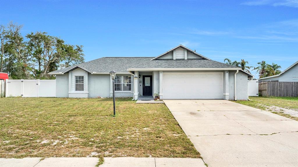 A single-story house with a gray exterior, a two-car garage, and a large front lawn — 1160 MANITOBA STREET, DELTONA, FL