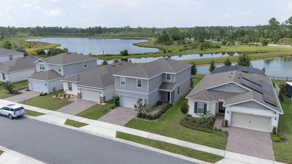 An aerial view shows several suburban houses with driveways and lawns near a large lake — 17684 SAW PALMETTO AVENUE, CLERMONT, FL