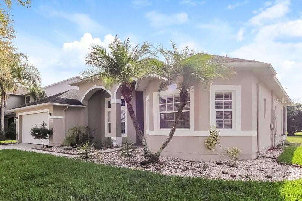 A single-story house with a beige stucco exterior, a two-car garage, and two palm trees — 4204 LUGANO COURT, KISSIMMEE, FL