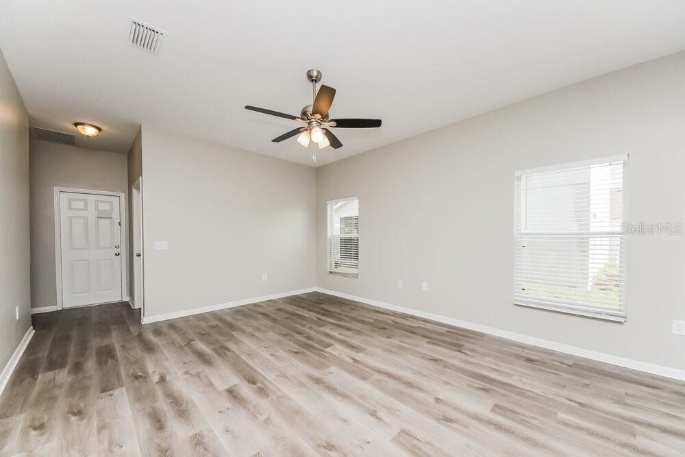 An empty room with light gray walls, wood-look flooring, a ceiling fan, and two windows — 4204 LUGANO COURT, KISSIMMEE, FL