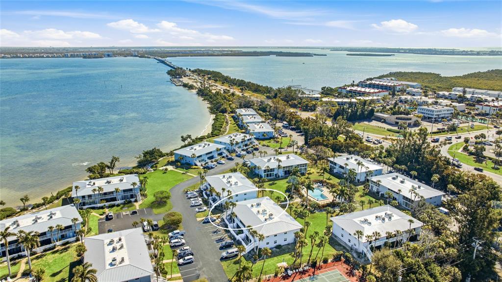 An aerial view shows a multi-story residential complex with a pool near the water — 600 MANATEE AVENUE UNIT 116, HOLMES BEACH, FL