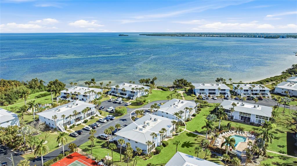 An aerial view shows a multi-story residential complex with white buildings near a coastal body of water — 600 MANATEE AVENUE UNIT 116, HOLMES BEACH, FL
