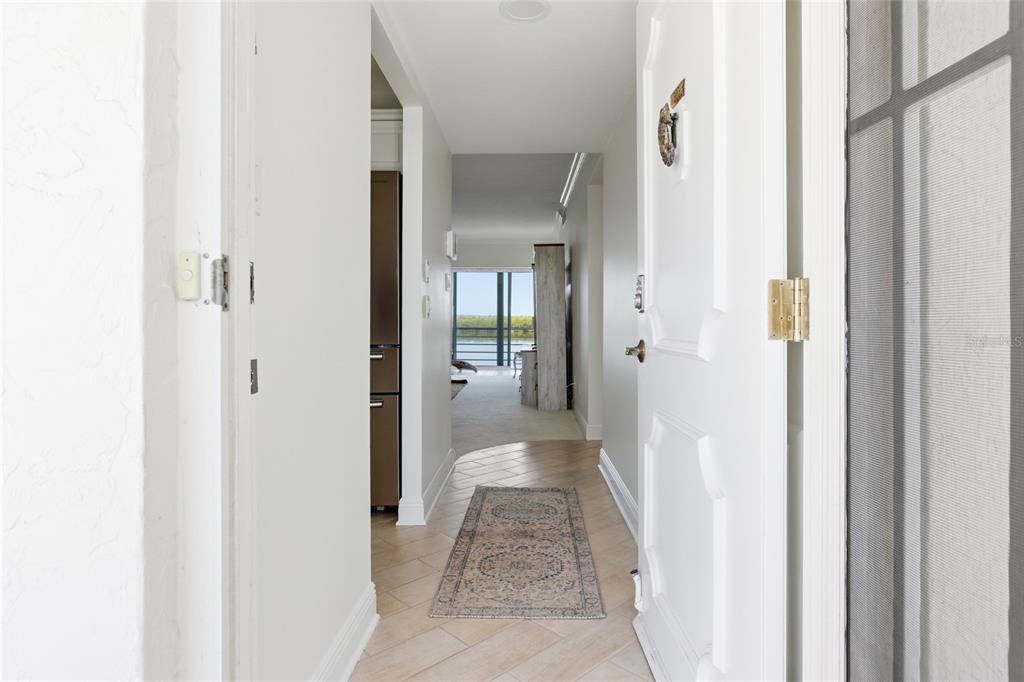A view from an entryway looking down a hallway toward a room with water views — 4420 EXETER DRIVE UNIT 303, LONGBOAT KEY, FL