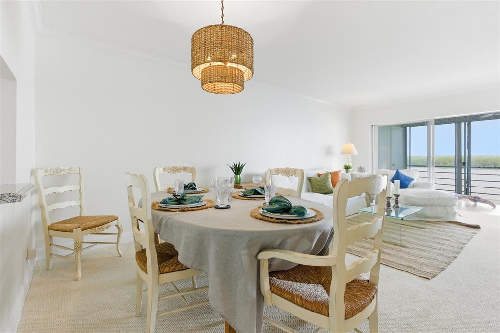 A dining area with a woven pendant light and chairs sits beside a living room — 4420 EXETER DRIVE UNIT 303, LONGBOAT KEY, FL