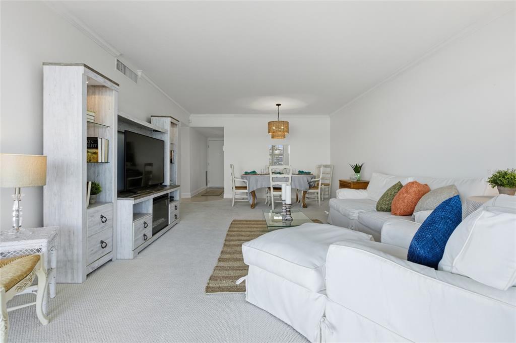 A living and dining room features white furniture, a television console, and light carpeting — 4420 EXETER DRIVE UNIT 303, LONGBOAT KEY, FL