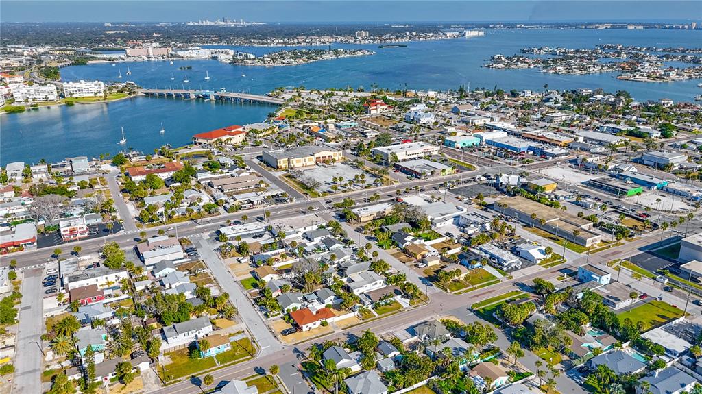 An aerial view shows a coastal town with houses, commercial buildings, and a bridge over water — 500 78TH AVENUE, ST PETE BEACH, FL