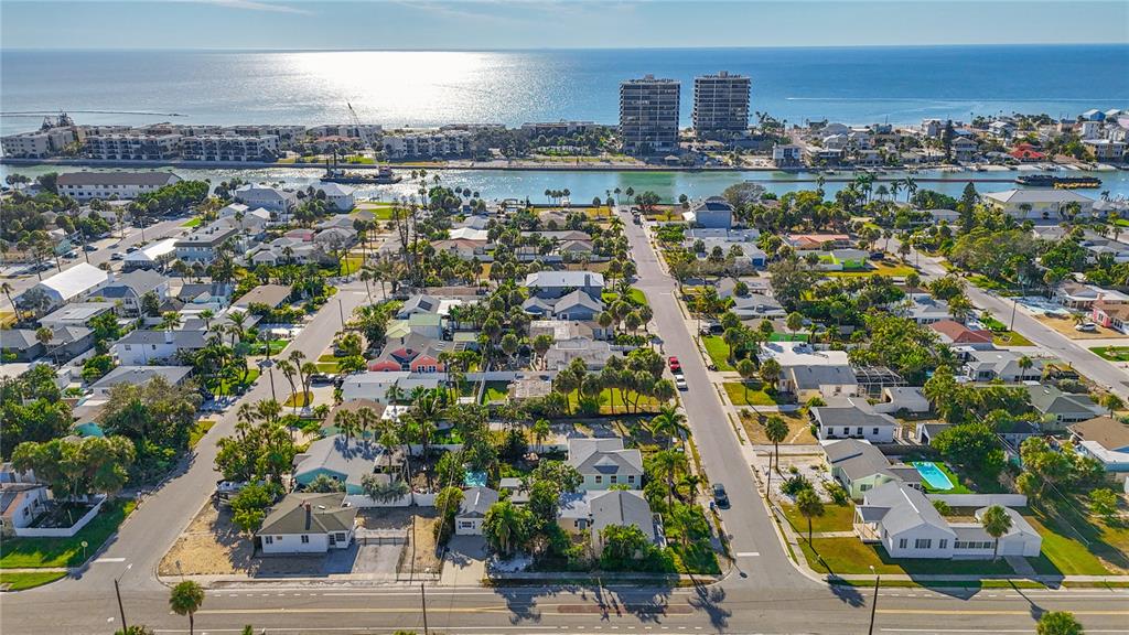 An aerial view shows a coastal neighborhood with houses, palm trees, and a nearby waterway — 500 78TH AVENUE, ST PETE BEACH, FL