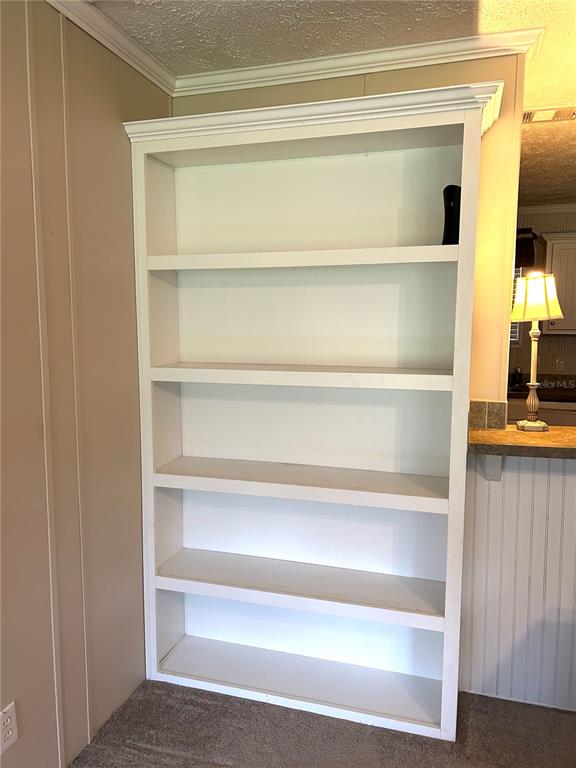 A white built-in bookshelf with five shelves stands against a beige wall on carpet — 13191 NE 9TH STREET, WILLISTON, FL