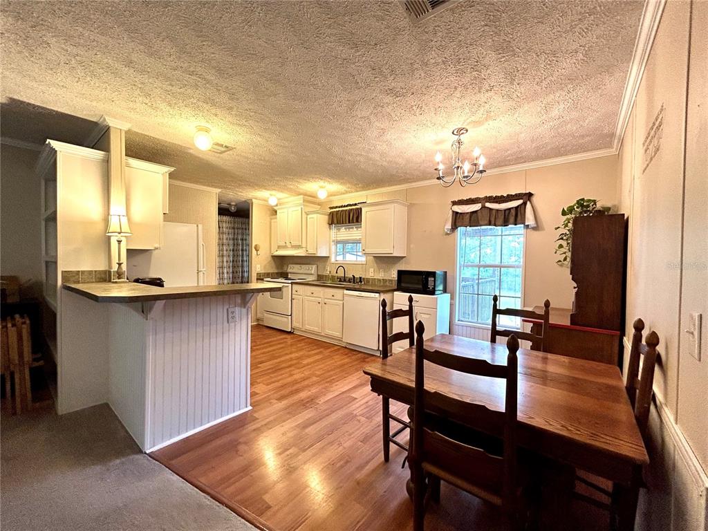 A kitchen and dining area with white cabinets, wood-look flooring, and a breakfast bar — 13191 NE 9TH STREET, WILLISTON, FL