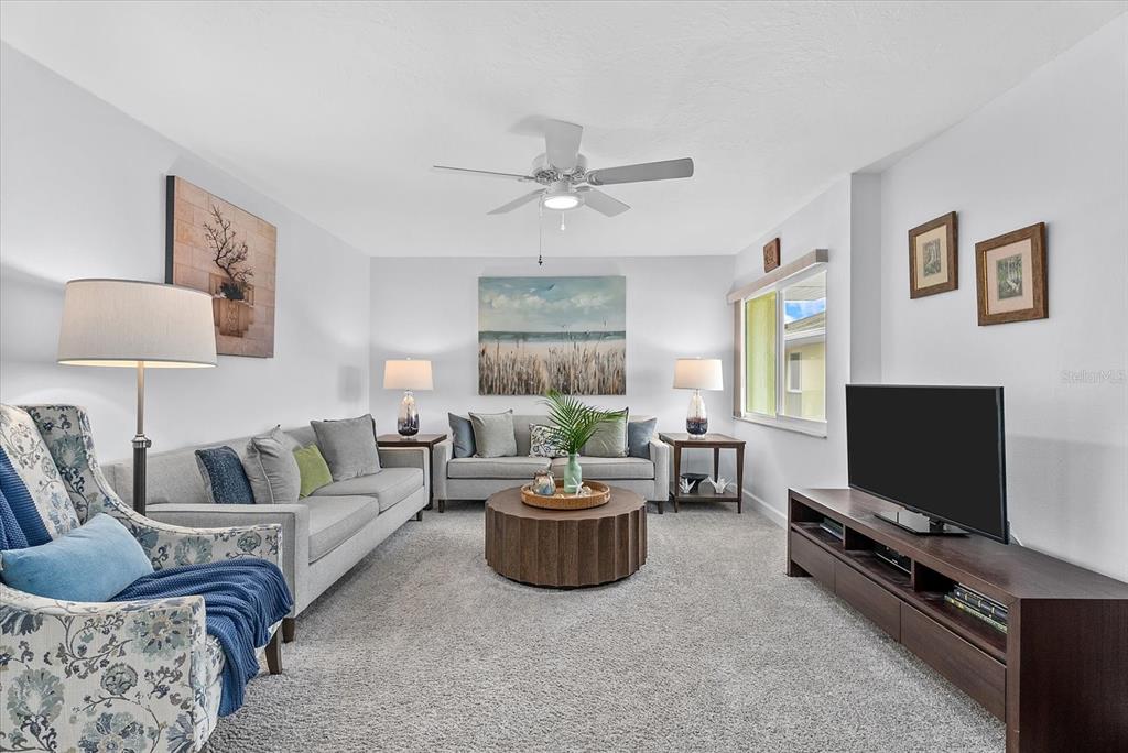 A screened-in balcony overlooks a grassy yard, a neighboring building, and a distant lake — 101 LOUELLA LANE UNIT 10, NOKOMIS, FL