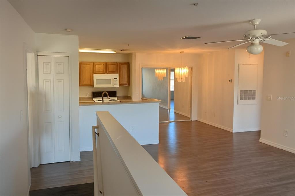 An interior view showing a kitchen with wood cabinets, a dining area, and wood-look flooring — 4850 51ST STREET W UNIT 1203, BRADENTON, FL