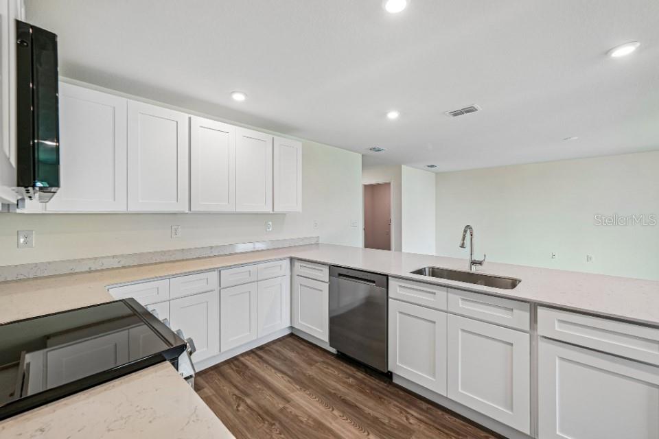 A kitchen features white shaker cabinets, quartz countertops, stainless steel appliances, and wood-look flooring — 3442 W EUNICE DRIVE, DUNNELLON, FL